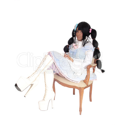 A baby doll woman sitting in armchair.