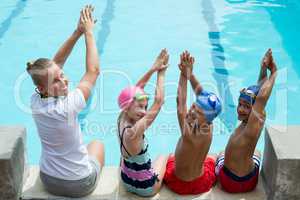 Swimming instructor with students at pool side