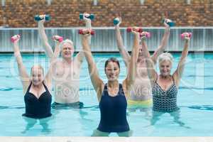 Female instructor with senior swimmers exercising in swimming pool