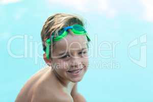 Smiling little boy wearing green swimming goggles