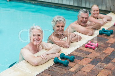 Swimmers leaning by dumbbells at poolside