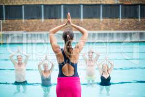 Yoga instructor assisting senior swimmers at poolside