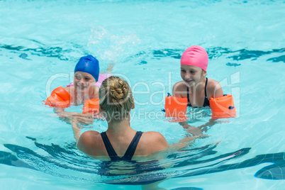 Female instructor helping girls in swimming pool