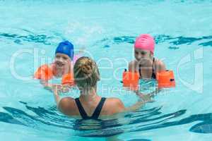 Female instructor helping girls in swimming pool