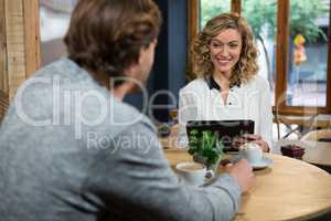 Smiling woman looking at man at table in coffee shop