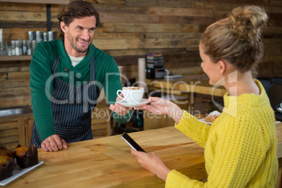 Barista serving coffee to female customer in cafeteria
