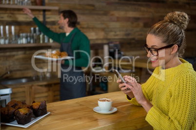 Happy woman using mobile phone in coffee shop
