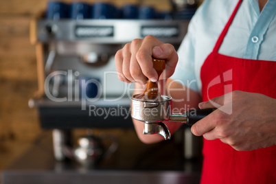 Barista using tamper to press ground coffee into portafilter in cafe