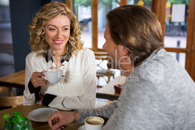 Woman having coffee while looking at man in cafe