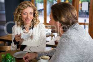 Woman having coffee while looking at man in cafe