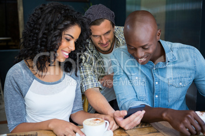 Friends using mobile phone in coffee shop