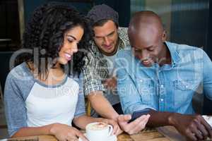 Friends using mobile phone in coffee shop