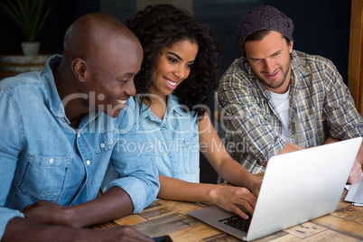 Happy friends using laptop in coffee shop