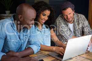 Happy friends using laptop in coffee shop