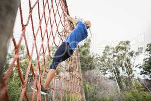 Woman climbing a net during obstacle course