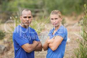 Fit man and woman standing with arms crossed during boot camp training