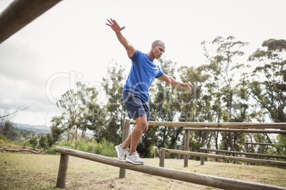 Fit man balancing on hurdles during obstacle course training