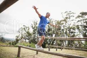 Fit man balancing on hurdles during obstacle course training