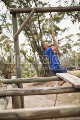 Fit man climbing a rope during obstacle course