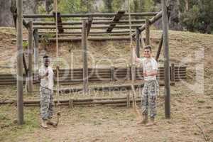 Military soldiers showing thumbs while holding rope during boot camp training