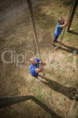 Fit person climbing down the rope during obstacle course