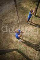Fit person climbing down the rope during obstacle course
