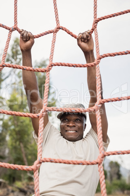 Military soldier climbing a net during obstacle course