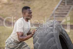 Determined military soldiers exercising with tyre