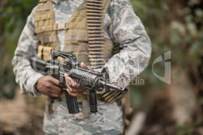 Mid section of military soldier holding a rifle