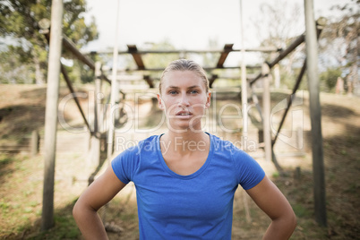 Portrait of fit woman standing with hands on hip during obstacle course