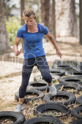 Woman running over the tyre during obstacle course