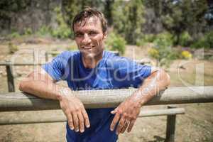 Smiling man leaning on a hurdle during obstacle course