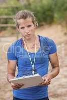 Portrait of female trainer holding clipboard during obstacle course