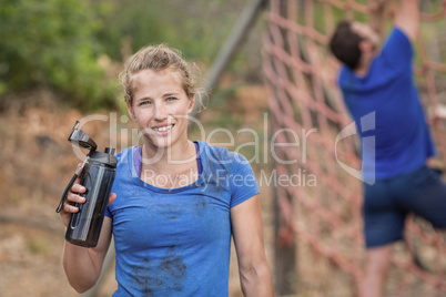 Portrait of woman holding water bottle during obstacle course