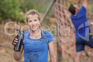Portrait of woman holding water bottle during obstacle course