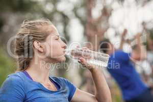 Woman drinking water from bottle during obstacle course