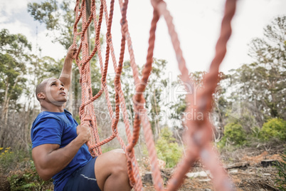 Fit man climbing a net during obstacle course