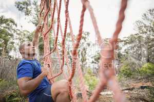 Fit man climbing a net during obstacle course