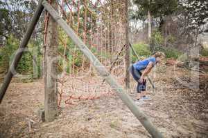 Tired woman bend down with hands on knees during obstacle course