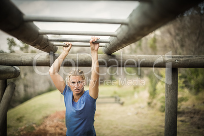 Fit woman climbing monkey bars during obstacle course
