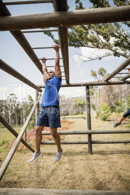 Fit man climbing monkey bars during obstacle course