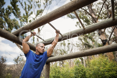 Fit man climbing monkey bars during obstacle course