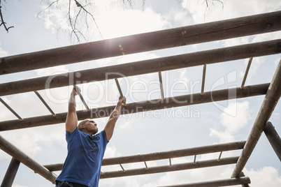 Fit man climbing monkey bars during obstacle course