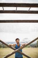 Portrait of fit man leaning on wooden bar during obstacle course