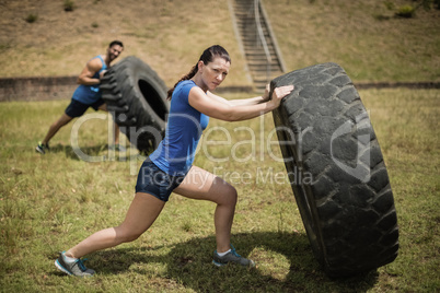 Man and woman flipping a tire during obstacle course