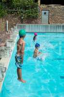 Swimmers jumping in swimming pool at leisure center