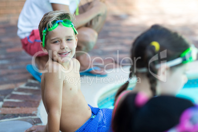 little boy sitting with friends at poolside