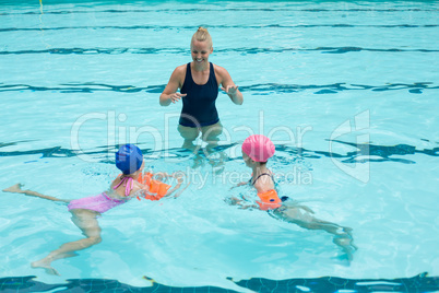 Happy instructor assisting children in swimming pool