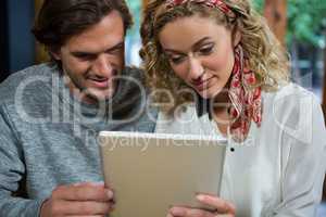 Couple using digital tablet in coffee shop