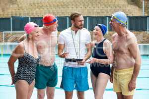 Seniors people with instructor standing at poolside